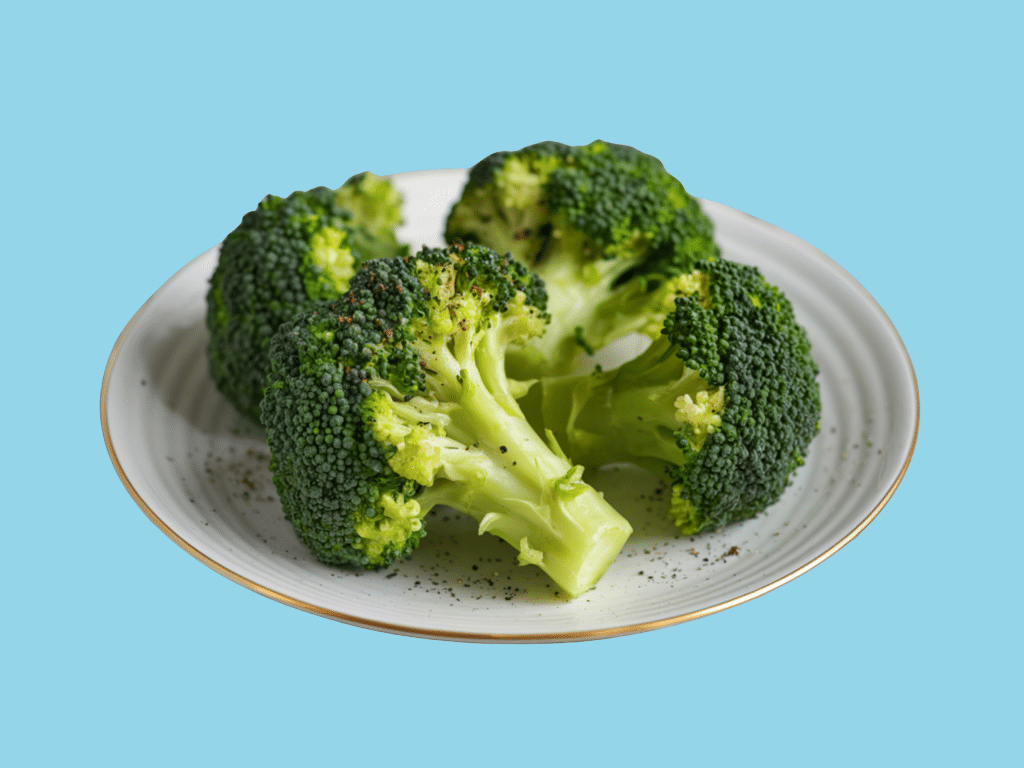 Image of broccoli for post on fibermaxxing. Broccoli is on a white plate with a light blue background.